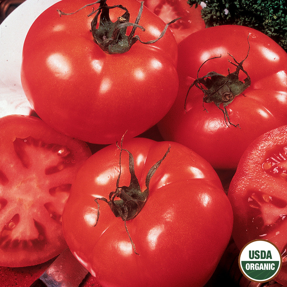 A cluster of ripe red tomatoes with one cut in half, displaying the inside. There is a USDA Organic label on the image.