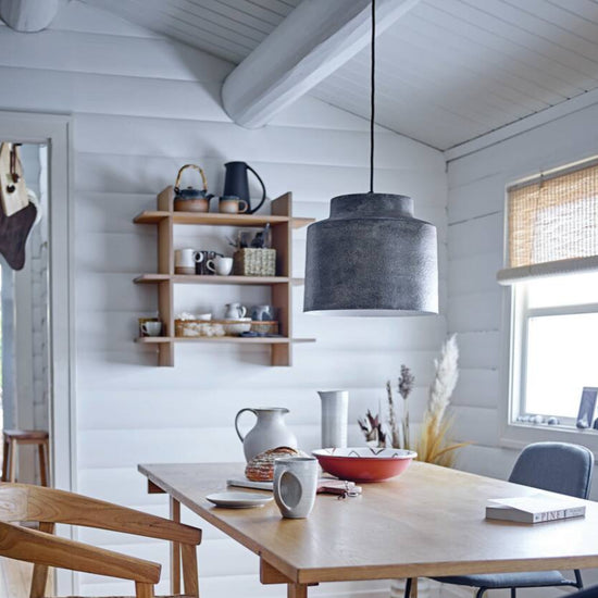A black stoneware pitcher with a matte finish, featuring a handle and spout for pouring on display in a kitchen