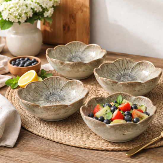 Set of ceramic bowls on a wooden table with fruit salad and flowers in the background