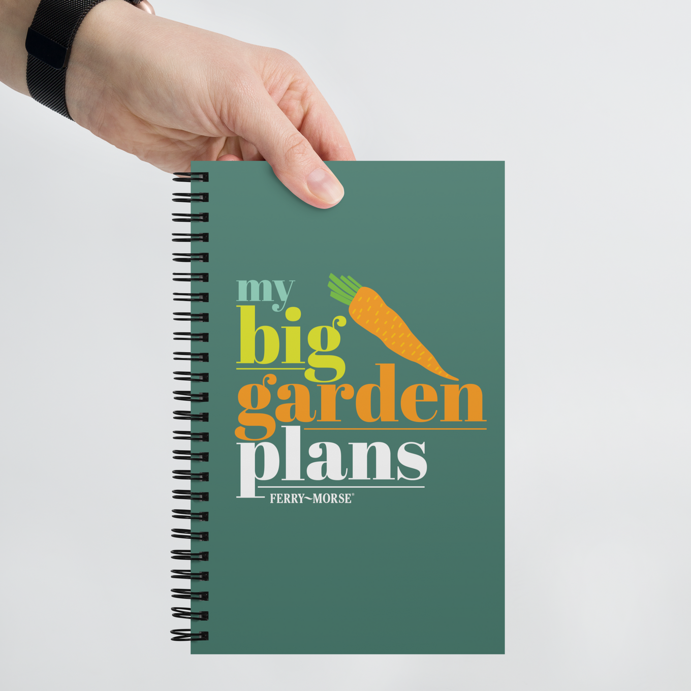 A green spiral-bound notebook with the title 'my big garden plans' printed on the cover, alongside an illustration of a carrot.