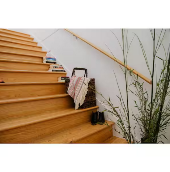 Wooden staircase with books and a basket on the steps, next to a plant.