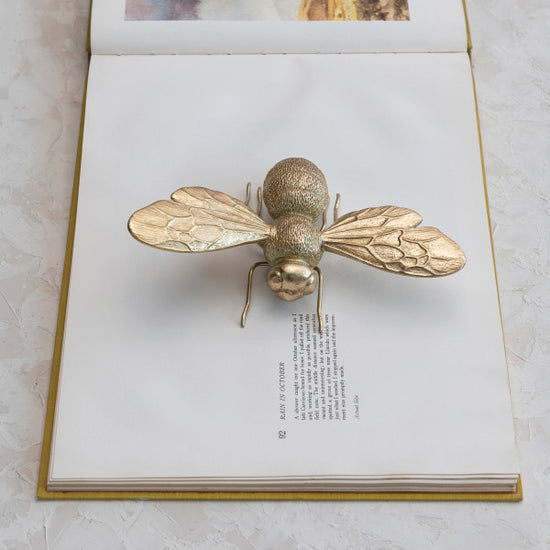 A decorative figurine of a bee with gold finish.