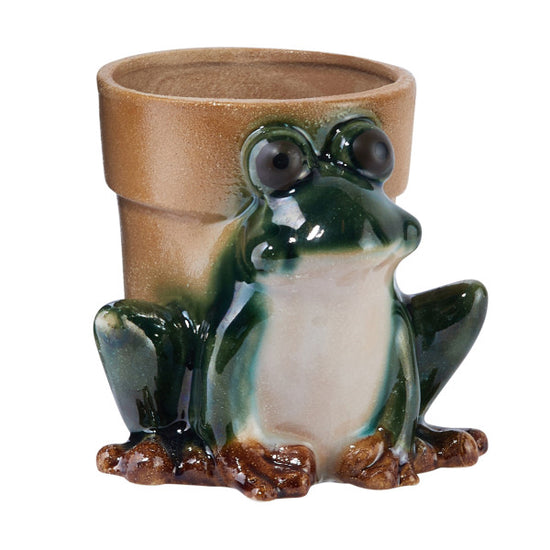 A stoneware frog planter with a round body and a smiling face, primarily green with white and brown details.