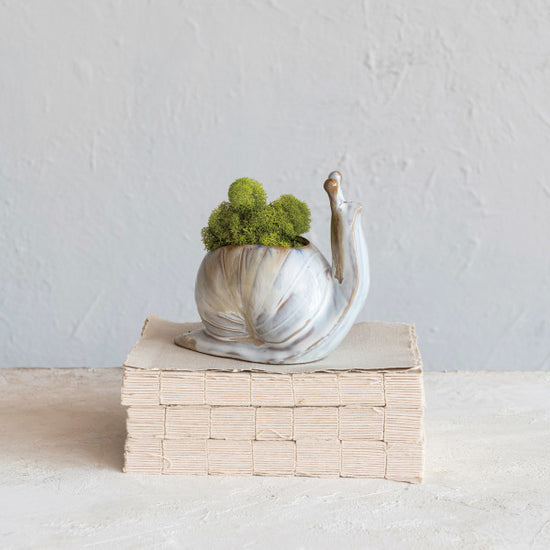 A stoneware snail-shaped planter with a reactive glaze creating multicolored patterns on its surface.