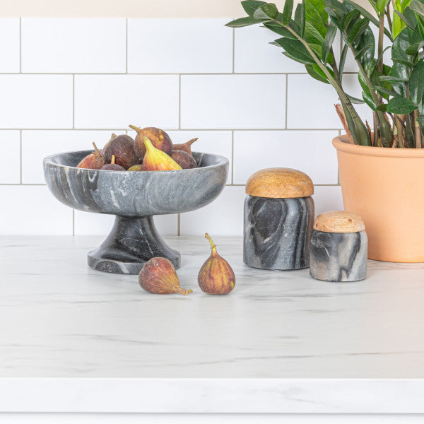 A round grey marble pedestal bowl with a smooth finish, sitting on a sturdy base.