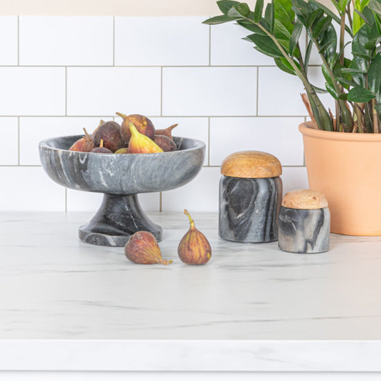 A round grey marble pedestal bowl with a smooth finish, sitting on a sturdy base.