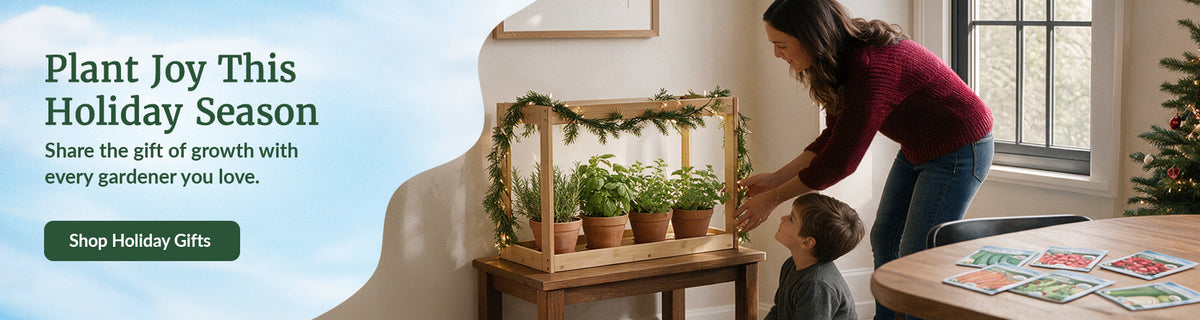 woman and child next to bamboo grow light with herbs in it. Holiday tree in the corner with seed packets on the table. Callout says, "Plant joy this holiday season; share the gift of growth with every gardener you love," with a button that says " Shop Holiday Gifts "