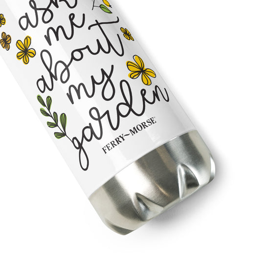 A stainless steel water bottle with double-wall construction, featuring a white body with text and small floral designs. The cap is silver, and the bottle is labeled with the phrase 'Ask me about my garden'.