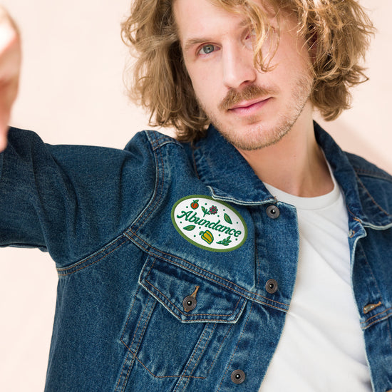 Man wearing a denim jacket with a patch on a beige background