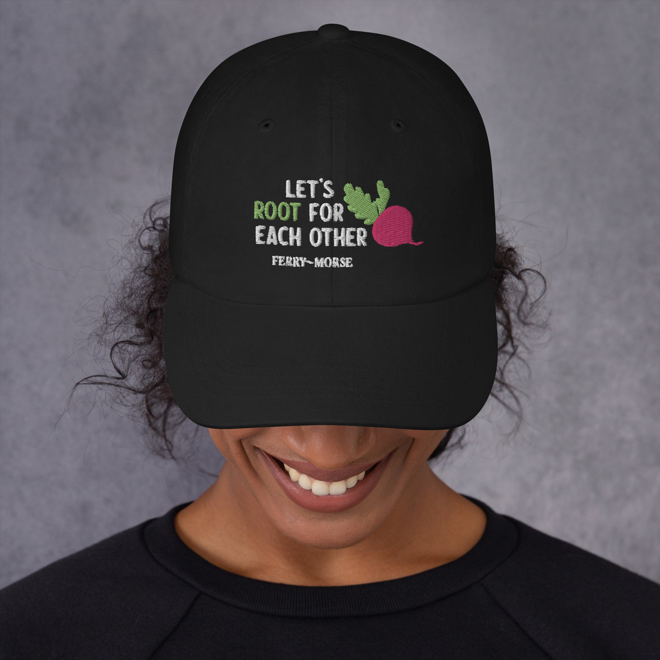 A black hat with the text 'LET'S ROOT FOR EACH OTHER' and a graphic of a root vegetable on it on female model