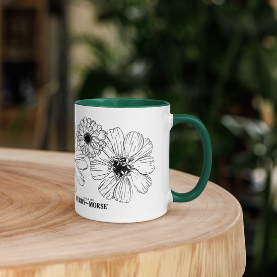 A white ceramic mug with a green rim and handle, featuring a black and gray zinnia flower design and the text 'My Morning Buzz'.