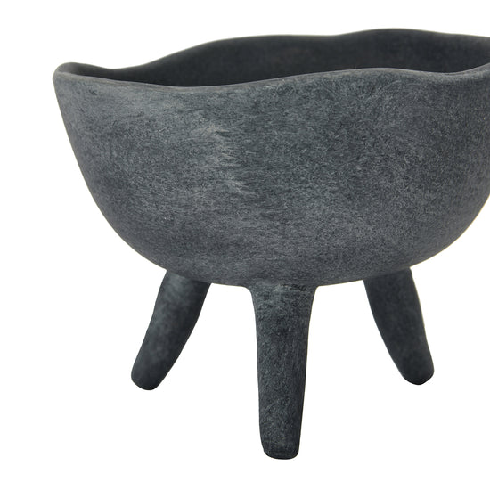 A matte black terracotta footed planter with an asymmetrical edge.