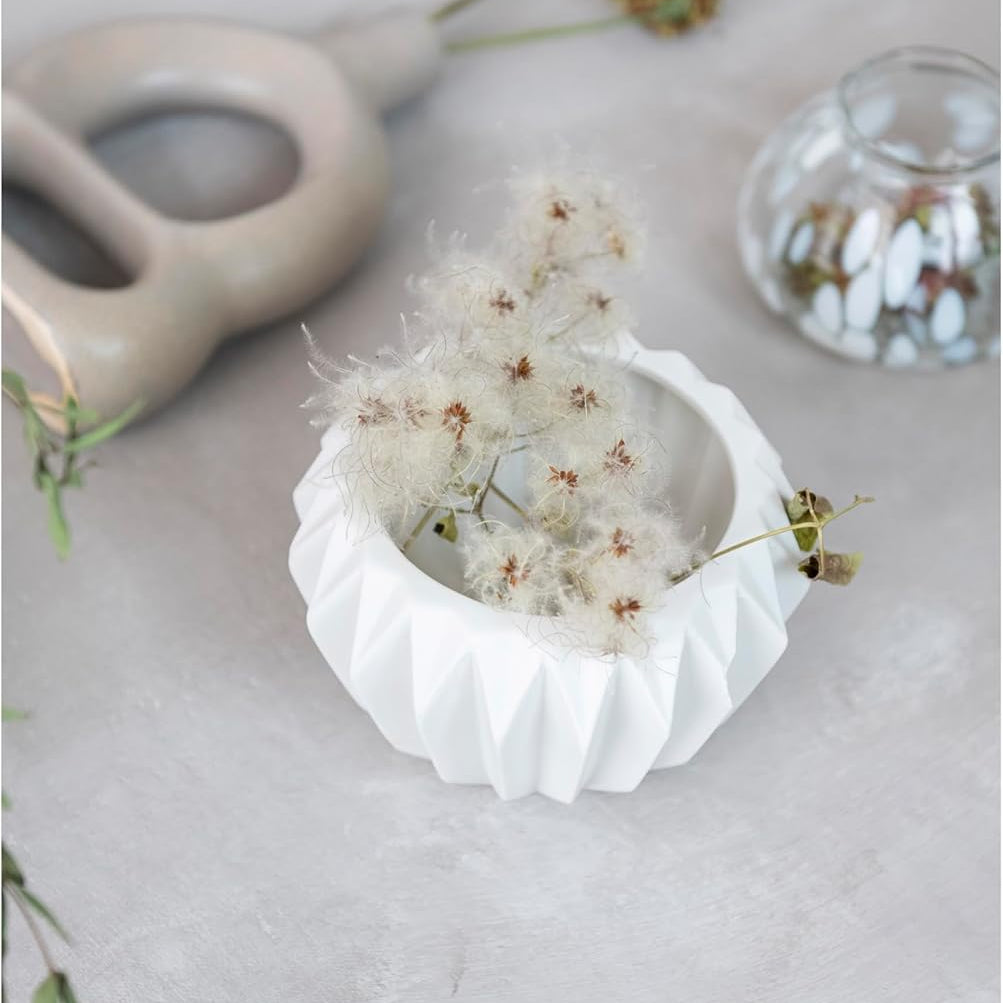 Small white ceramic bowl with dried flowers on a light gray surface