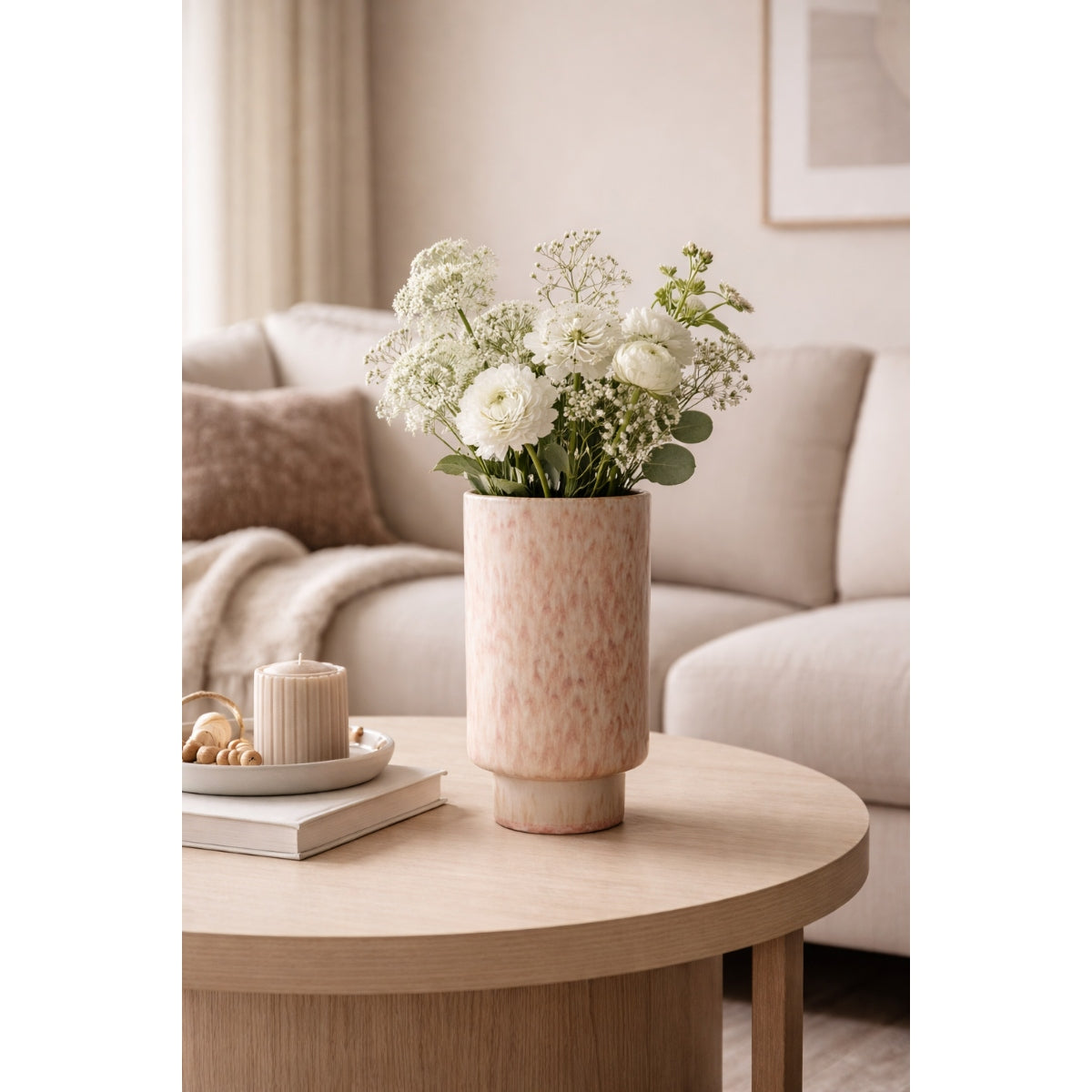 Floral arrangement in a vase on a wooden coffee table with a neutral-colored sofa in the background.