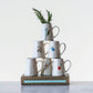White ceramic pitchers with floral design and bird designs stacked on top of each other