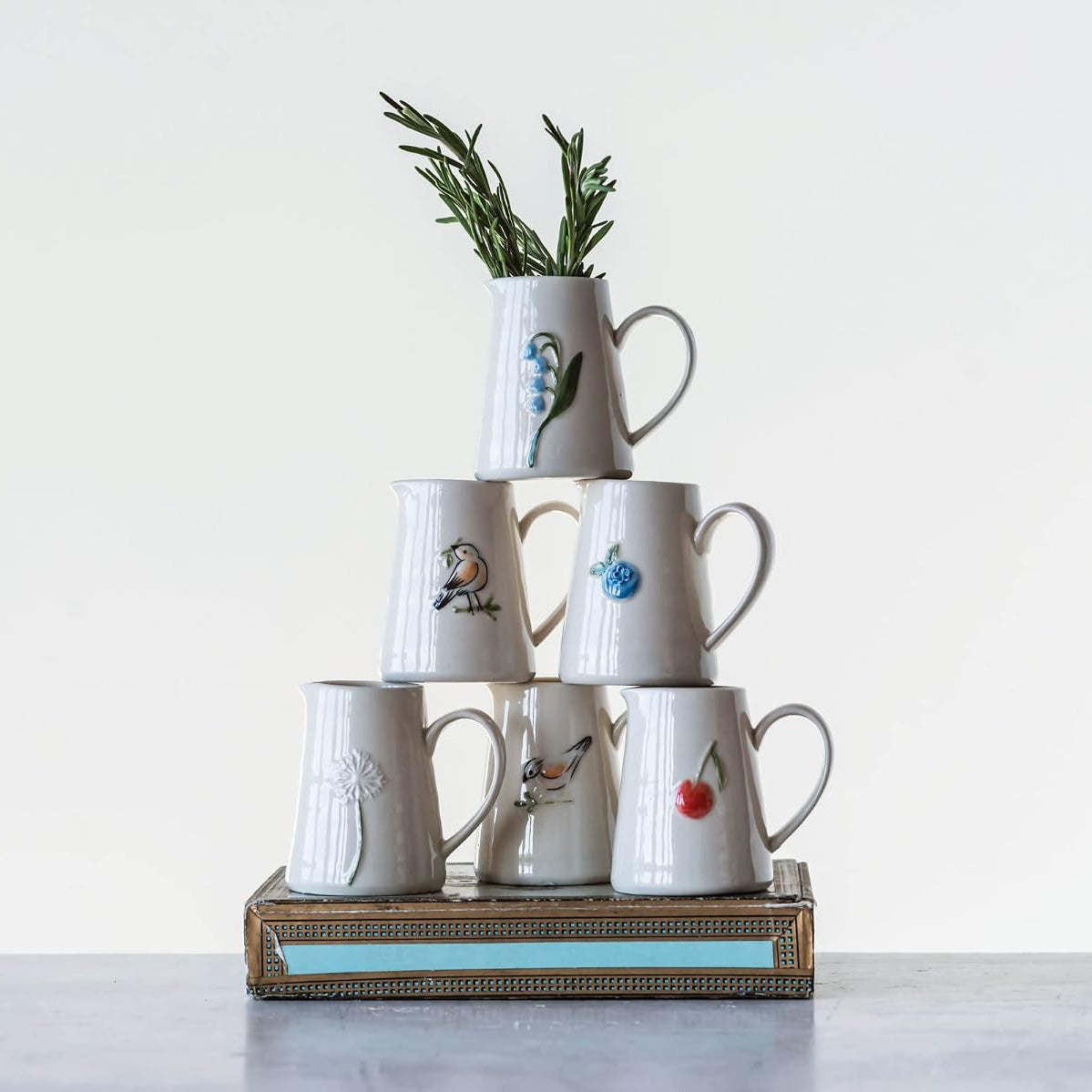 White ceramic pitchers with floral design and bird designs stacked on top of each other