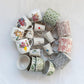 White ceramic pitchers with floral design and bird designs mixed in with a collection of colorful bowls and mugs