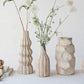 Three textured vases with floral arrangements on a light surface against a white background