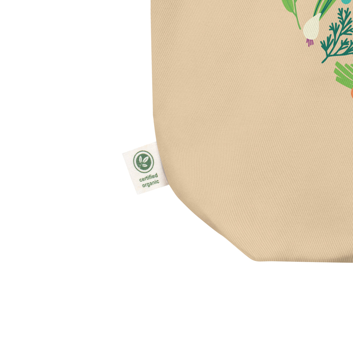 Close-up of a beige woven fabric product corner with a small white Certified Organic tag and partial vegetable print in green, white, and orange on the right side, against a white background.
