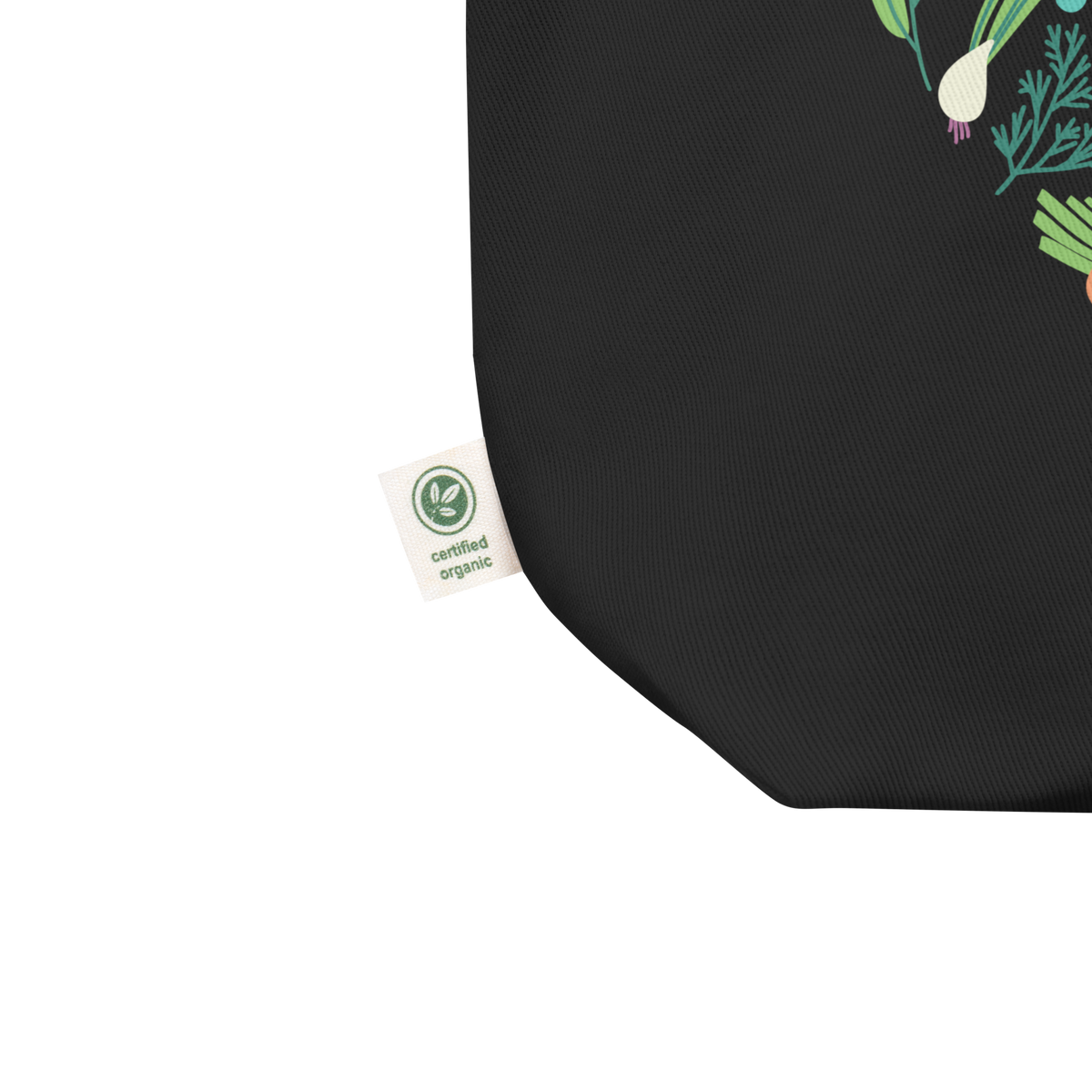 Close-up of a black fabric product corner with a small white Certified Organic tag and part of a green vegetable print on a white background.