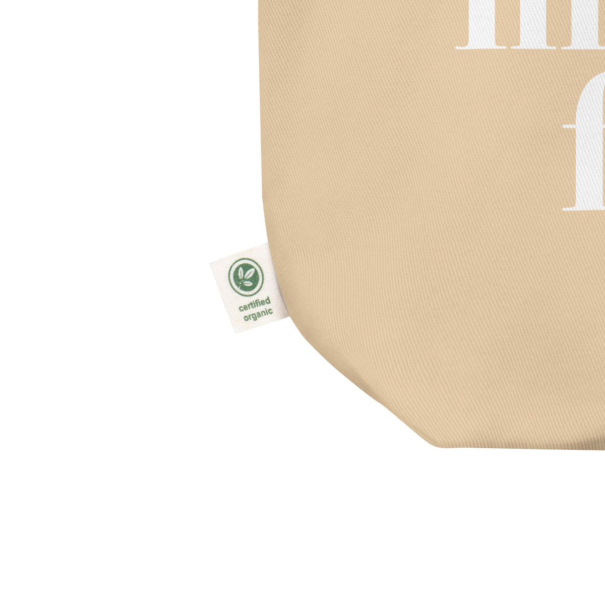 Close-up of a beige fabric product corner with a small white Certified Organic tag attached, on a white background.