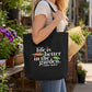 A woman in a white t-shirt and blue jeans carries a black canvas tote bag with the printed quote 'life is better in the garden.' and a small carrot and leaf graphic.