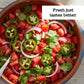 Salad with tomatoes, jalapeños, and onions in a terracotta bowl with text 'Fresh just tastes better'.