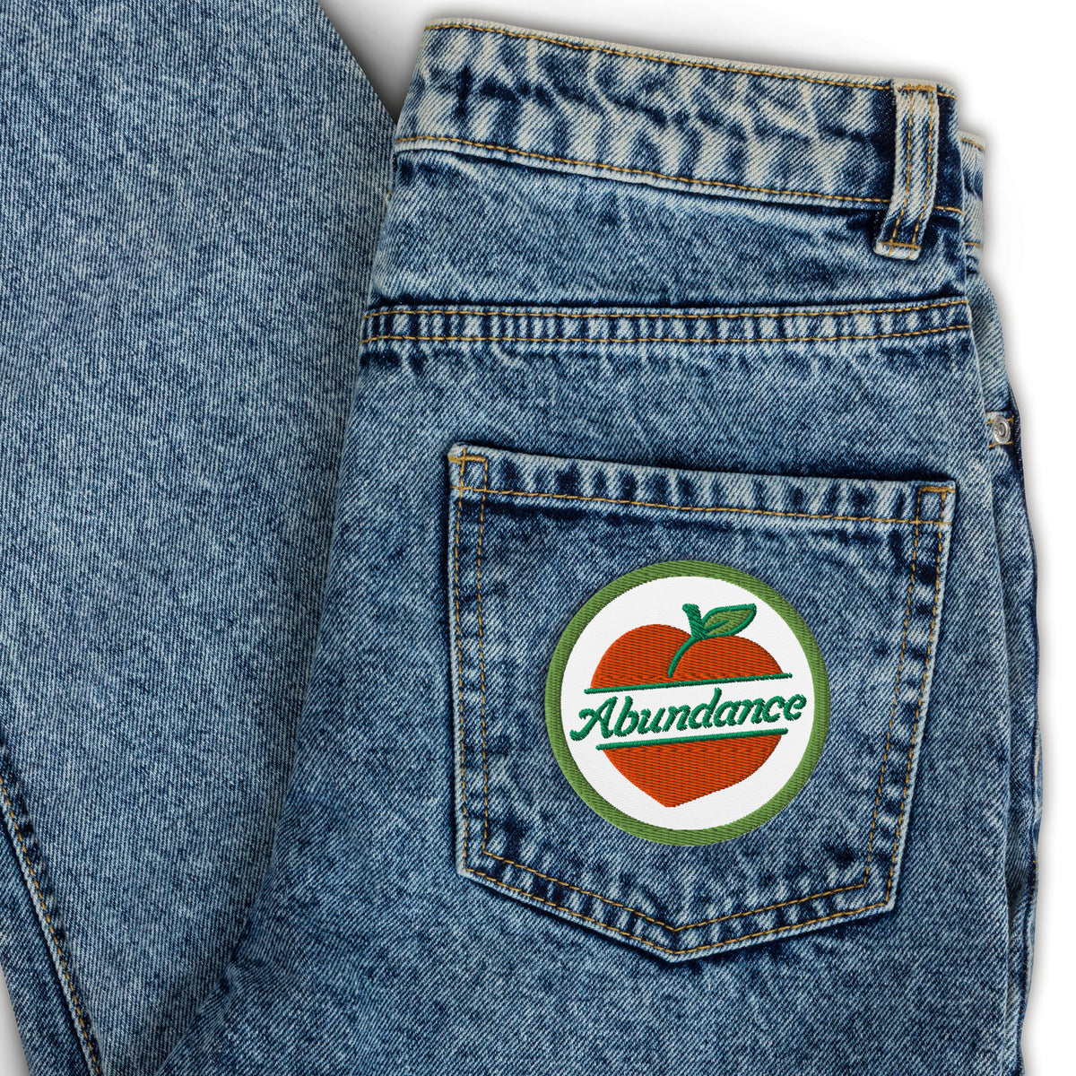 Blue denim jeans with a 'Abundance' patch on the back pocket.
