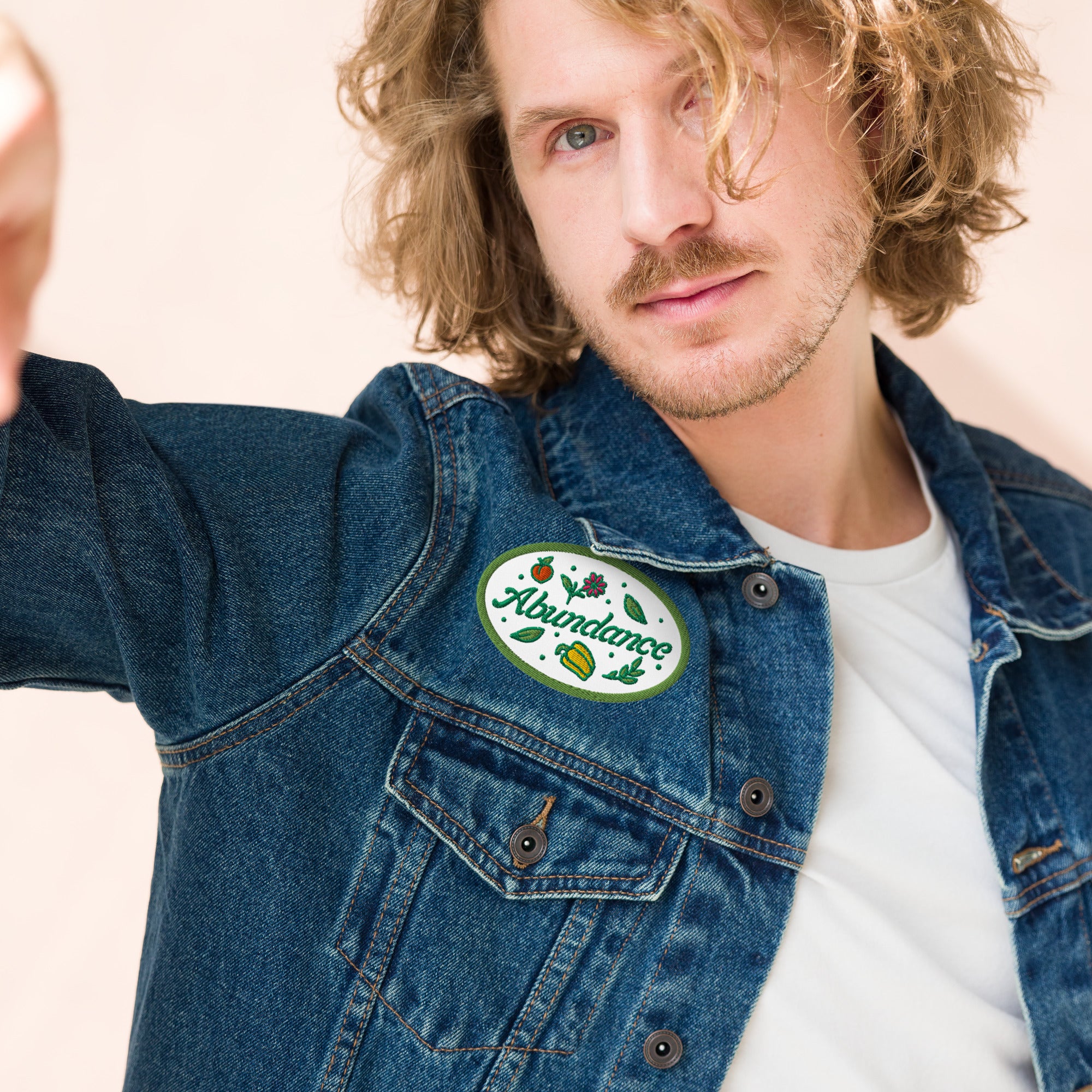 Man wearing a denim jacket with a patch on a beige background