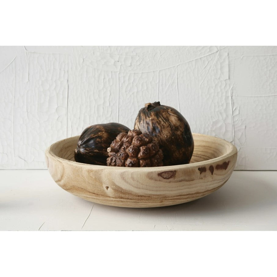 Wooden bowl with dark fruits on a white surface and light gray textured wall background